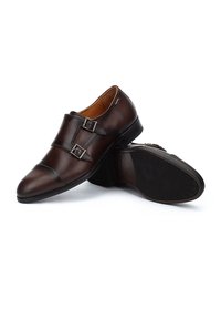 Bruine leren schoenen met een slank ontwerp, voorzien van dubbele gesps accentuering, een ronde neus en een gestructureerde zwarte rubberen zool.