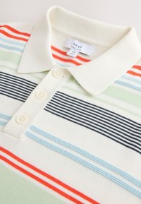 Polo couleur crème avec des rayures horizontales rouges, noires, bleues et vertes et trois boutons sur le devant, taille moyenne, coupe normale.