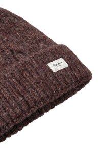 Gorra de lana marrón tejida con hilo texturizado y un dobladillo doblado. Presenta una etiqueta de tela blanca con texto negro.