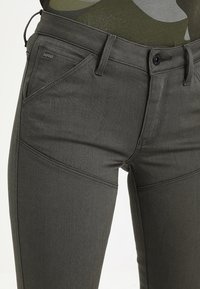 Mörkgrå jeans i denim med slim fit, med vinklade framfickor och stängning med svart knapp. Diskreta sömmar synliga.