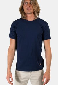 T-shirt a maniche corte blu navy realizzato in tessuto morbido, con colletto a girocollo e una piccola etichetta con logo in basso a sinistra.
