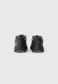 Juoda ir pilka Skechers sportbačių pora, matoma iš nugaros, ant šviesaus vientiso fono.