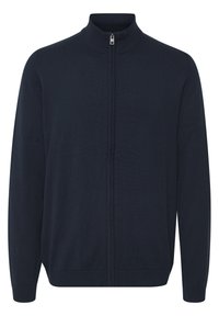 Marine blå zip-up cardigan laget av strikket stoff. Har høy krage, lange ermer og ribbede mansjetter og kant. Glatt tekstur, minimalistisk design.