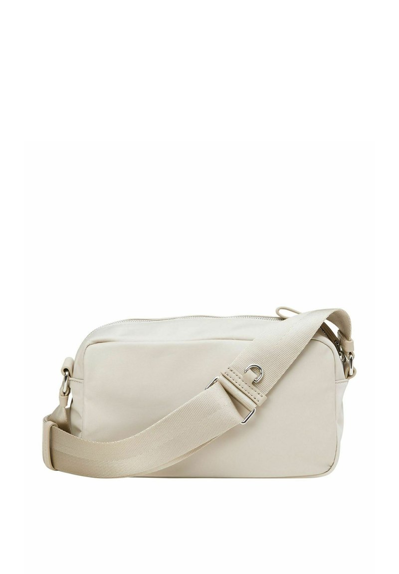 Beżowa torebka na ramię wykonana z gładkiego materiału, z zamkiem błyskawicznym i regulowanym paskiem z metalowymi elementami. Prostokątny kształt, minimalistyczny design.