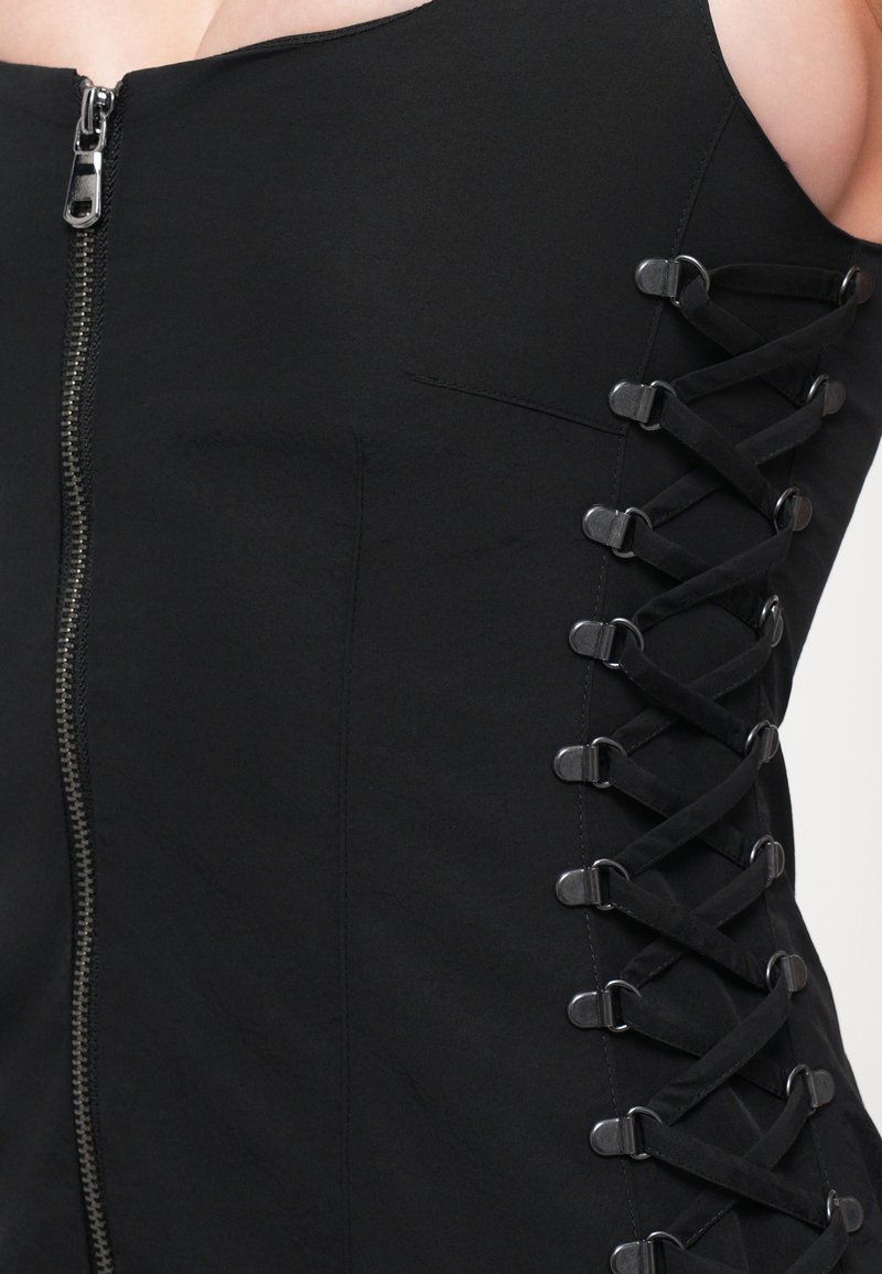 Svart klänning med dragkedja fram och snörningsdetalj på sidan med metallöglor. Slät tyg med en figurnära design.