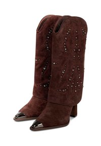 Brązowe zamszowe kozaki do kolan z ćwiekowanymi detalami, spiczastym noskiem i metalowymi akcentami na czubku; gruba pięta dla stabilności.