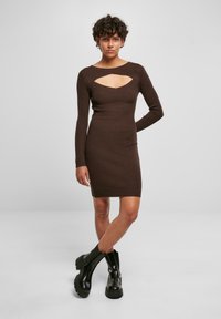 Abito in maglia a coste marrone con maniche lunghe e dettaglio collo a chiave, silhouette aderente, abbinato a stivali alla caviglia neri e chunky.