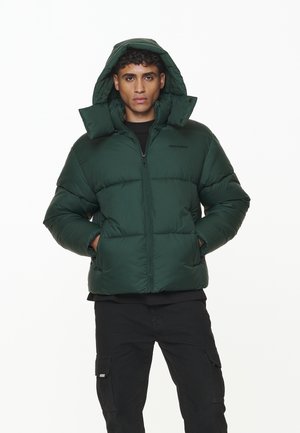 Dark green puffer jacket with a hood, featuring a front zip, quilted design, and two side pockets. The fabric appears smooth and insulated.