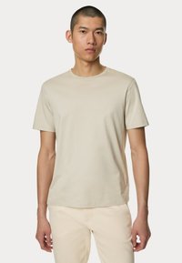 Beige t-shirt med korte ærmer lavet af blødt stof, med en rund hals og et enkelt design uden synlige mønstre eller detaljer.