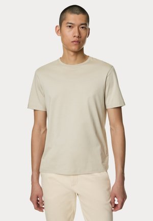 Camiseta de manga corta beige hecha de tela suave, con cuello redondo y un diseño sencillo sin patrones ni acentos visibles.