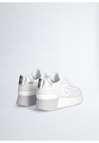 Sneakers bianchi con una parte superiore in rete testurizzata e dettagli in suede. Presentano un tab sul tallone argentato e una suola piatta bianca chunky.