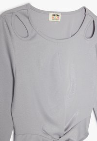 Grijs geribbelde lange mouwen shirt met een ronde halslijn, uitsnijdingen op de schouders en een geknoopte zoom. Gemaakt van een gestructureerde, rekbare stof.