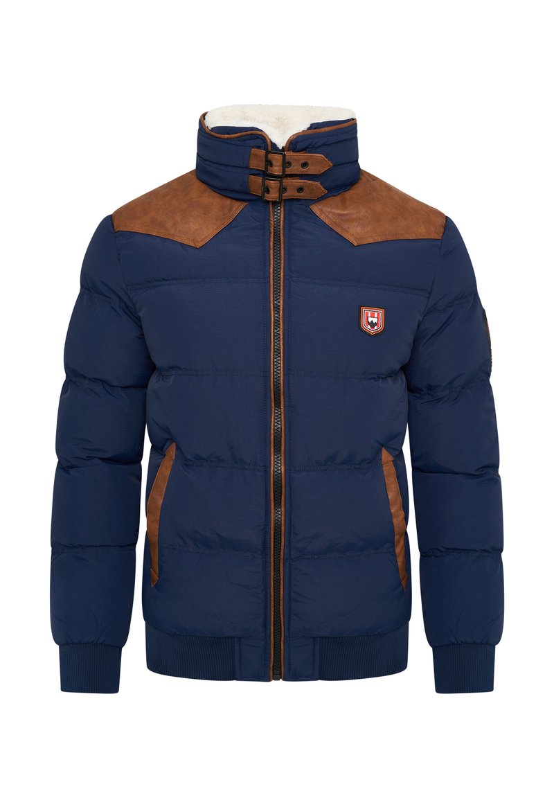 Marineblaue Pufferjacke mit braunen Leder-Schulterpatches, Reißverschluss, hohem Kragen, gerippten Manschetten und Seitentaschen. Mit einem Abzeichen auf der Brust.