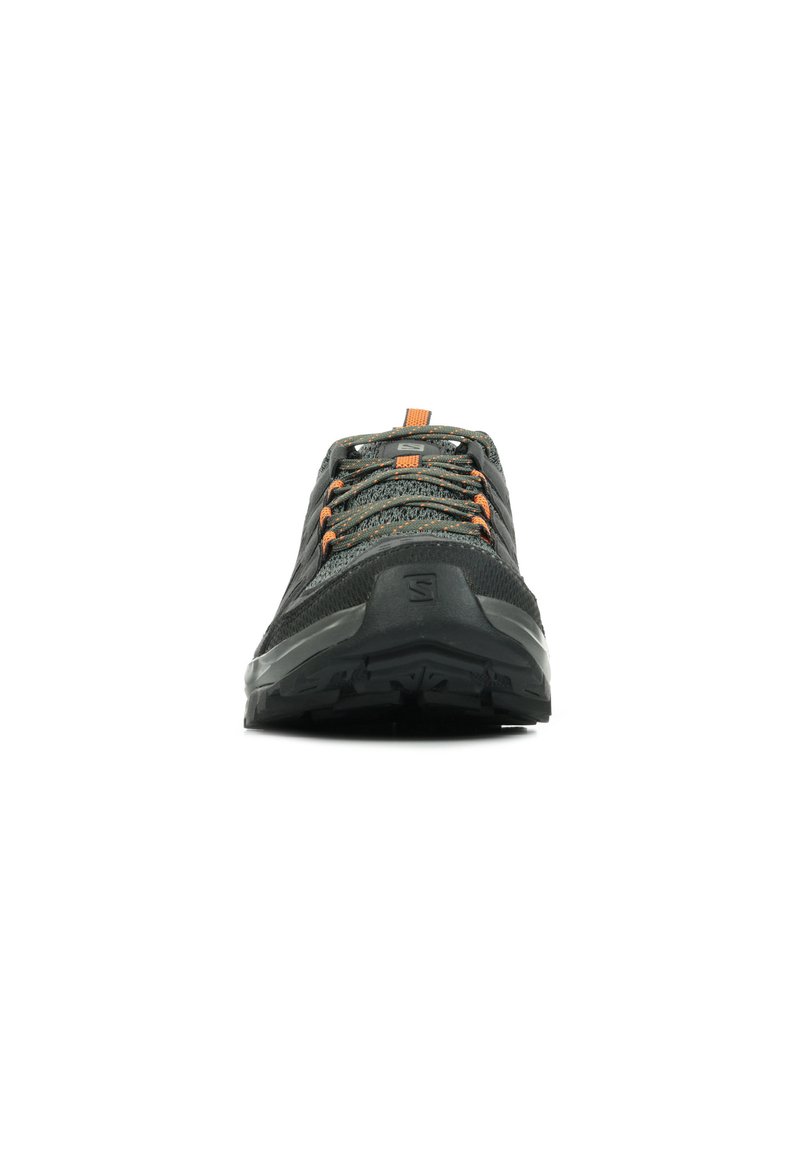 Zapatilla deportiva negra con parte superior texturizada, acentos en naranja en los cordones y una suela robusta diseñada para tracción. Vista frontal.