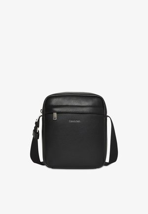 Black Calvin Klein textured leather crossbody bag with adjustable strap and front zippered pocket.