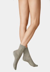 Grüne gerippte Knöchelsocken mit einem strukturierten Muster. Hergestellt aus einem weichen, dehnbaren Material, das dafür sorgt, dass sie eng am Knöchel sitzen.