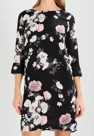 Schwarzes knielanges Kleid mit rosa-weißem Blumenmuster, dreiviertel Ärmeln und rundem Ausschnitt, getragen von einer stehenden Person.