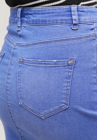 Ljust blå denimhögmidjade jeans med en figursydd passform, som har två bakfickor, ett klassiskt sömmönster och metallknappdetaljer.