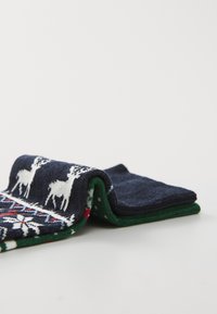 Ciorapi tricotati cu o bază albastră închisă, având un model alb cu reni și accente roșii. Manșete verzi și material texturat cu un design festiv.
