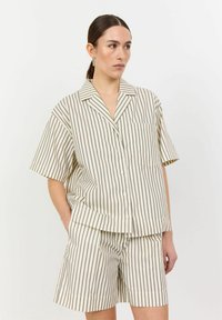 Lightweight, cream-colored pajama set featuring contrasting dark stripes, short sleeves, and button-up design with a chest pocket.
