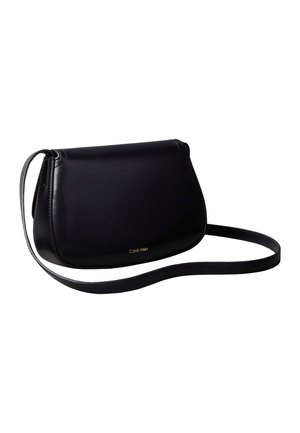 Sac à épaule en cuir noir avec une forme incurvée et une fine bandoulière, petit logo doré Calvin Klein centré près de la base.