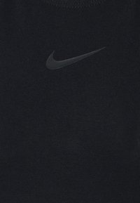 Svart atletisk topp i ribbat tyg med en liten svart Nike swoosh-logga fram. Enkel design med rund halsringning.