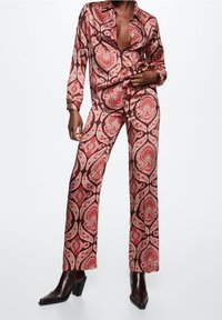 Ensemble à deux pièces à motif paisley marron, comprenant une chemise à col et à boutons ainsi qu'un pantalon évasé assorti ; fabriqué dans un tissu doux.