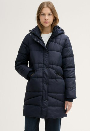 Navy modrá péřová bunda s kapucí, má zipový uzávěr, druky, šikmé švy a boční kapsy. Materiál vypadá jako nylon.