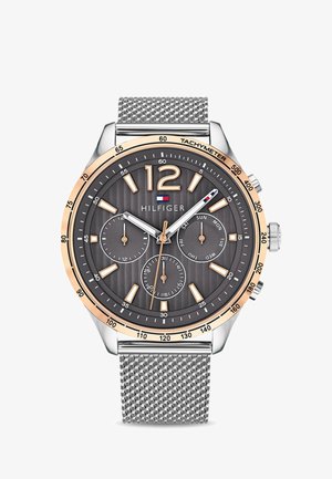 Zegarek w srebrnym odcieniu z szarym, teksturowanym cyferblatem, z złotą ramką i bransoletą typu mesh. Wskazania obejmują podcyfrowniki dnia i daty.