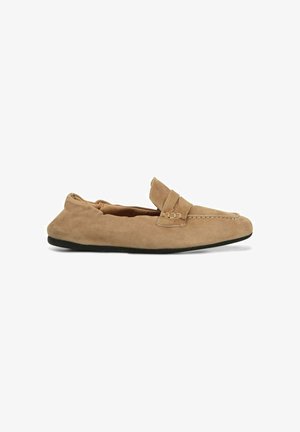 Mocassino in camoscio marrone chiaro con suola nera, cuciture in stile mocassino e dettaglio con cinturino sulla parte superiore, mostrato di profilo su sfondo bianco.