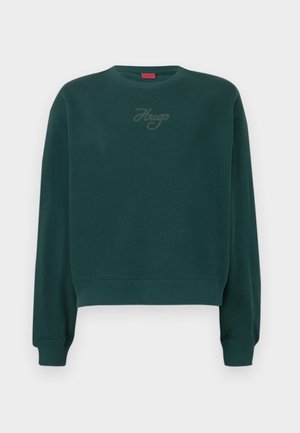 Roheline lühike sviiter, mis on valmistatud pehmest materjalist. Sellel on ribakujulised varrukad ja ääred ning diskreetne "Hugo" logo tikandina.