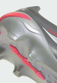 Szürke focicipő texturált felsőrésszel, piros részletekkel és kiemelkedő "Powerspine" díszítéssel. Formázott stoplikkal a jobb tapadás érdekében.