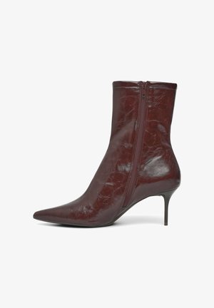 Braune spitz zulaufende Leder-High-Top-Stiefelette mit seitlichem Reißverschluss und dünnem Stiletto-Absatz auf weißem Hintergrund.