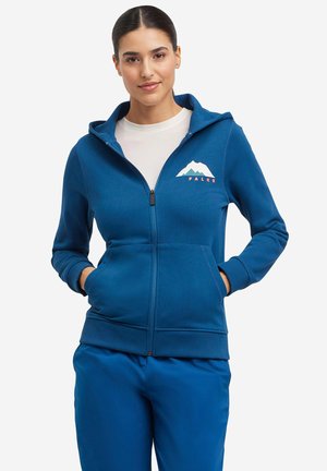 Felpa con zip blu in morbido tessuto, con una grafica di montagne e il logo "FALKE" sul lato sinistro del petto. Ha una vestibilità comoda e tasche.