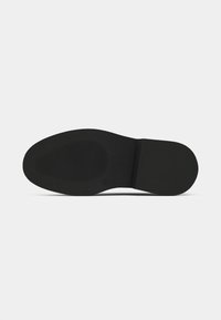 Sole di scarpa nera con superficie liscia, punta arrotondata e leggera texture antiscivolo. Nessun marchio visibile o motivi. Design semplice e piatto.