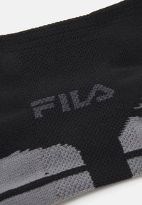 Textil texturat negru cu un logo „FILA” gri proeminent, cu un model de dungi diagonale gri în partea de jos.
