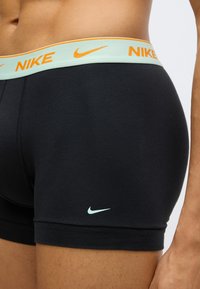 Mustad bokserpüksid hele sinise vöökohaga, millel on oranž "NIKE" kiri. Väike valge Nike logo alumises küljepoolses osas. Sile kangapind.