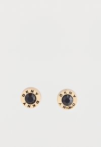 Boucles d'oreilles en forme de clou en ton or, avec une pierre noire facettée au centre et "DKNY" gravé sur le bord.