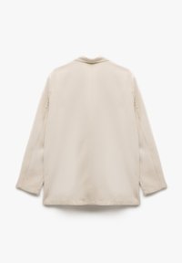 Blazer léger beige avec col, manches longues et coupe droite. Texture lisse avec des détails de couture minimalistes. Vue de dos.