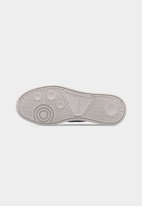 Semelle de chaussure en caoutchouc blanc avec une accroche texturée, des motifs circulaires sur le talon et l'avant-pied, et le nom de la marque "ALDO" embossé au centre.