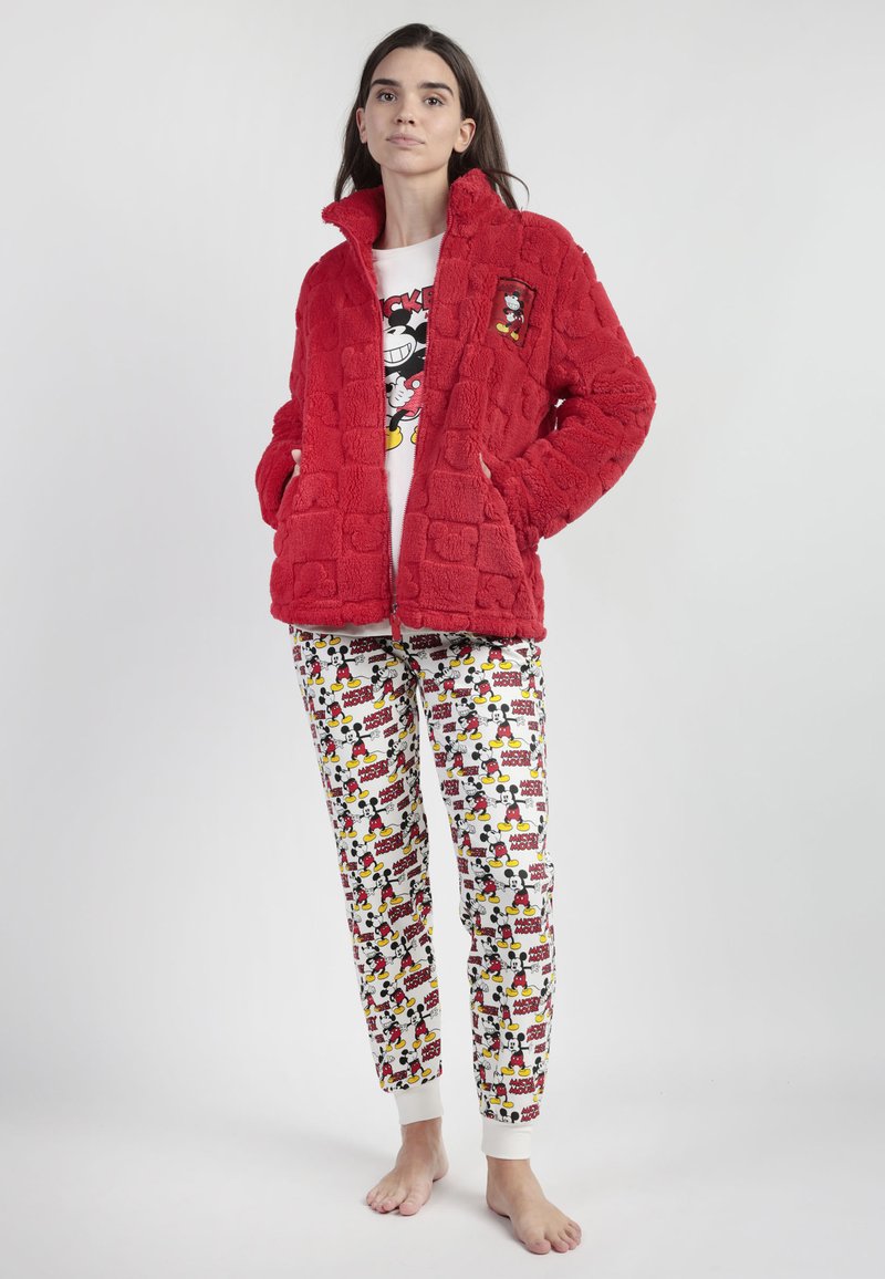 Chaqueta roja esponjosa con patrón de cuadros, con bolsillos laterales. Debajo, una camiseta blanca con un gráfico de Mickey Mouse. Pantalones de pijama impresos con diseño de dibujos animados.