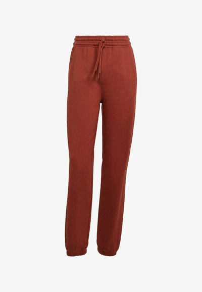 Spodnie dresowe w kolorze rdzy z elastycznym paskiem i mankietami, wyposażone w sznurek do regulacji oraz boczne kieszenie.
