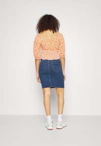 Floral, orange puff-sleeve top paired with a blue denim pencil skirt. The outfit features a fitted design and textured fabric.