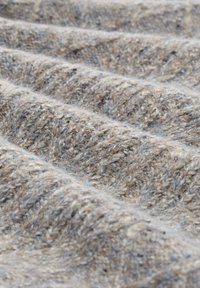 Strukturiertes gewebtes Stoff in Brauntönen und Beige, mit einer weichen, flauschigen Oberfläche und subtilen blauen Flecken, die in sanften Wellen angeordnet sind.