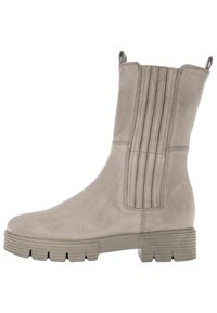 Beige Wildleder-Ankleboot mit abgerundetem Zehenbereich, gerippten Seitenpanelen und einer klobigen strukturierten Gummisohle. Verstärkte Fersenschlaufen für ein einfaches Anziehen.
