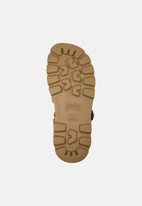 Brown shoe sole with deep treads, Camper logo, and size 42 markings visible against a plain light gray background.