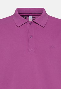 Polo viola con colletto, due bottoni e tessuto testurizzato. Presenta un piccolo logo sul lato sinistro.