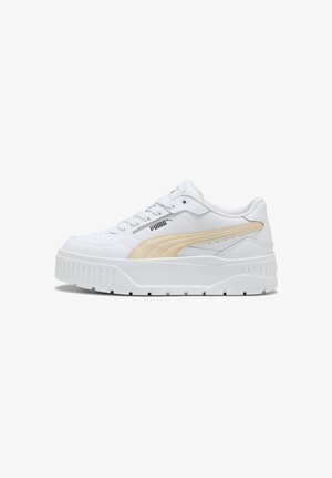 Sneaker bianca Puma con striscia beige, suola spessa, chiusura frontale con lacci e logo Puma nero sul lato, mostrata in profilo laterale su sfondo bianco.