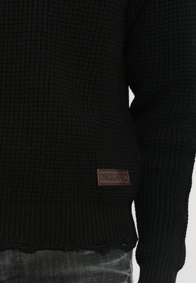 Pull noir en tricot avec un motif texturé, arborant une patch en cuir marron "DSQUARED" sur le côté gauche. Ourlet et poignets bordés.
