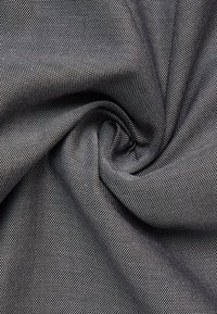 Textielstof met een soepele textuur, in een donkergrijze kleur met een subtiele ruitpatroon en fijne witte stippen die gelijkmatig verdeeld zijn.